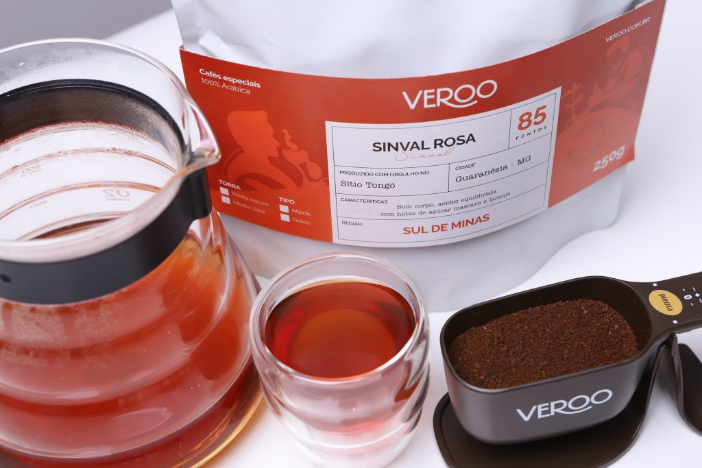 Foto da embalagem do café da edição de Setembro, Sinval Rosa Franco. Um copo borda dupla com café e uma balança pressca com café.